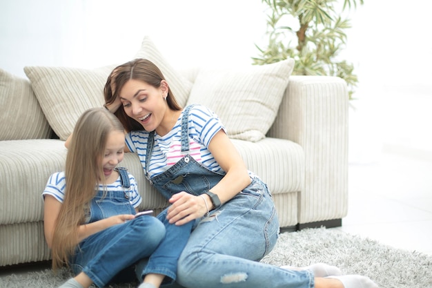 Mutter und ihre kleine Tochter verwenden ein Smartphone, um das Fotofoto mit Kopienraum anzuzeigen