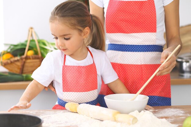 Mutter und ihre süße Tochter bereitet den Teig am Holztisch zu Hausgemachtes Gebäck für Brot oder Pizza Hintergrund der Bäckerei