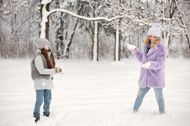 Mutter und ihre Tochter spielen im Winter in Schneebällen