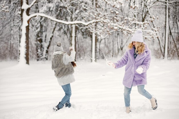 Mutter und ihre Tochter spielen im Winter in Schneebällen