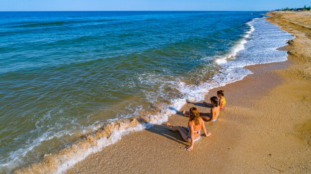 Mutter und ihre Töchter genießen den Meerblick, während sie in den Wellen am Meer sitzen