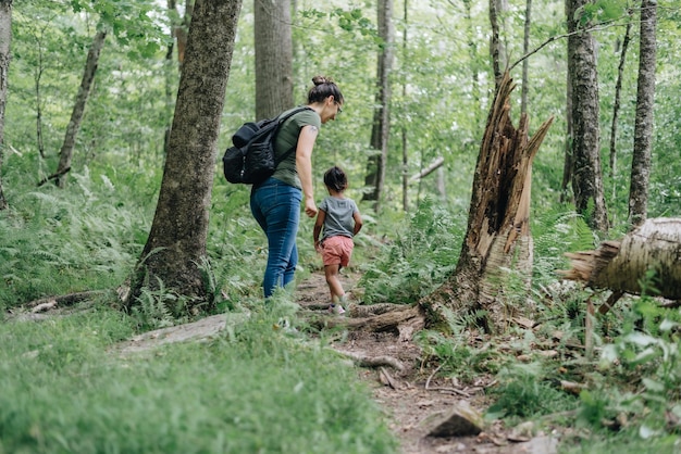 Mutter und junge Mischrasse-Tochter laufen auf einem Pfad im Wald