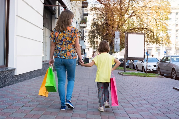 Mutter und Kind auf einer Straße mit Einkaufstüten