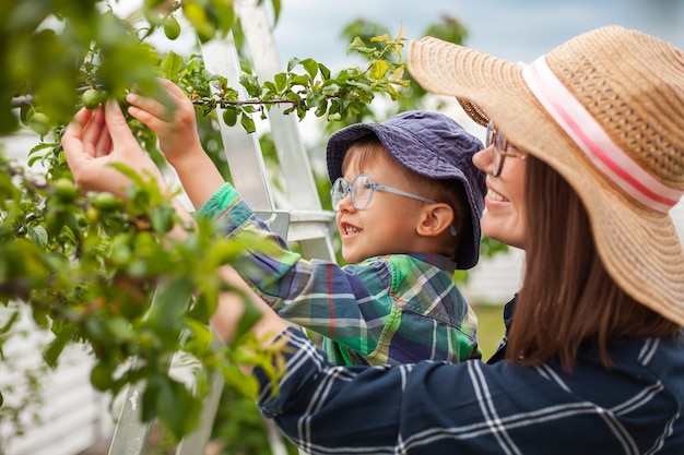 Mutter und Kind auf Leiterbaum, Gartenarbeit im Hinterhofgarten