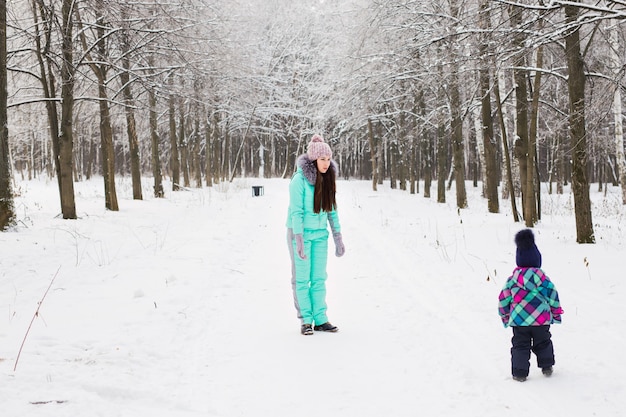 Mutter und Kind, die draußen schönen Wintertag genießen.