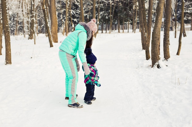 Mutter und Kind, die draußen schönen Wintertag genießen.