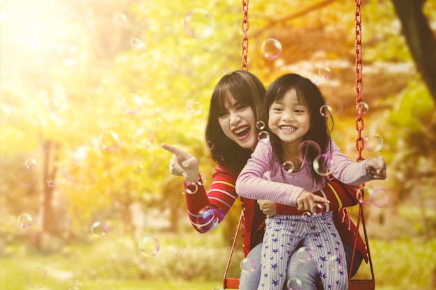 Mutter und Kind fangen Seifenblasen im Park