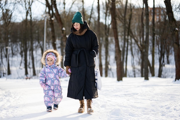 Mutter und Kind gehen an einem sonnigen, frostigen Wintertag im Park spazieren