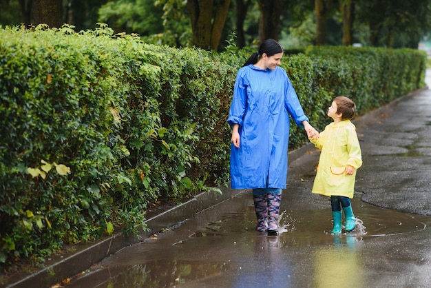 Mutter und Kind, Junge, spielen im Regen, tragen Stiefel und Regenmäntel