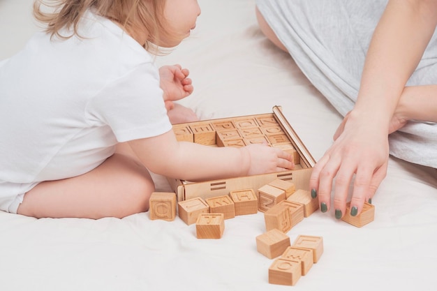 Mutter und Kind lernen das englische Alphabet in der Nähe Das Kind spielt mit Holzwürfeln mit englischen Buchstaben Das Konzept der frühkindlichen Vorschulerziehung zu Hause Lernspiele