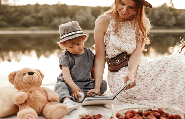 Mutter und Kind lesen Buch in der Nähe des Flusses