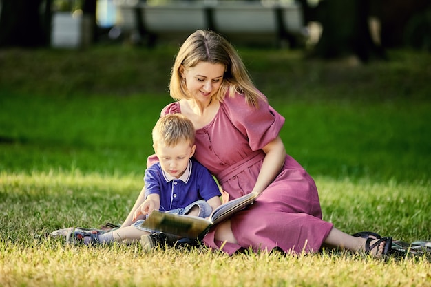 Mutter und Kind liegen auf Gras und lesen Buch im Freien