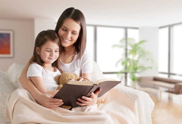 mutter und kind mädchen lesen ein buch im bett, bevor sie schlafen gehen