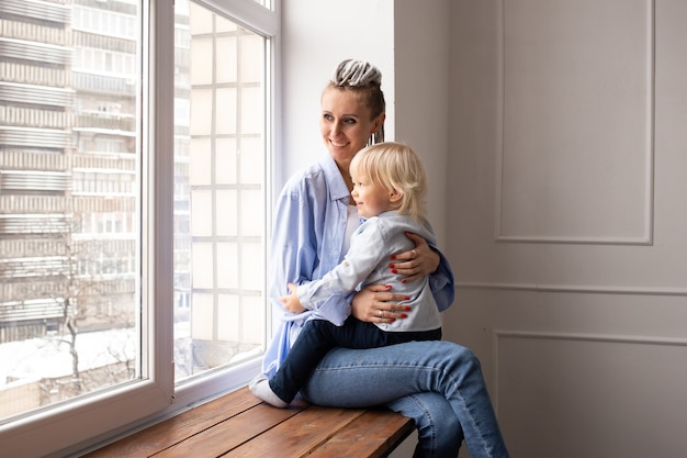 Mutter und Kind schauen durch Fenster zur Quarantänezeit