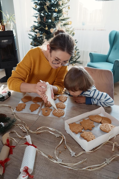 Mutter und Kind schmücken gemeinsam Weihnachtslebkuchen mit Puderzucker