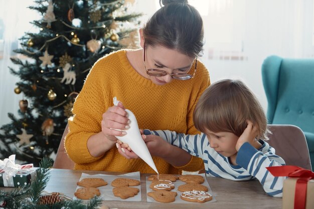 Mutter und Kind schmücken gemeinsam Weihnachtslebkuchen mit Puderzucker