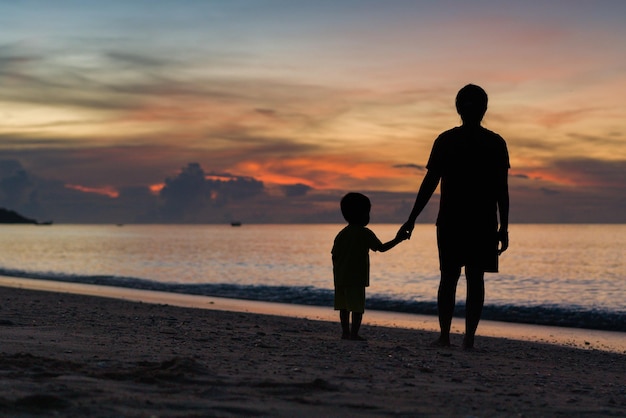 Mutter und Kind stehen bei Sonnenuntergang am Strand.