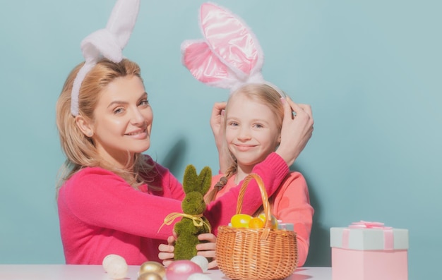 Mutter und Kind Tochter feiern Ostern süßes kleines Mädchen mit lustigem Gesicht in Hasenohren lachend...