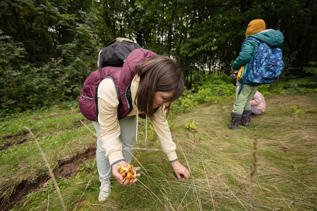 Mutter und Kinder auf der Suche nach Pilzen im wilden Wald Frau hält Butterblumenpilz