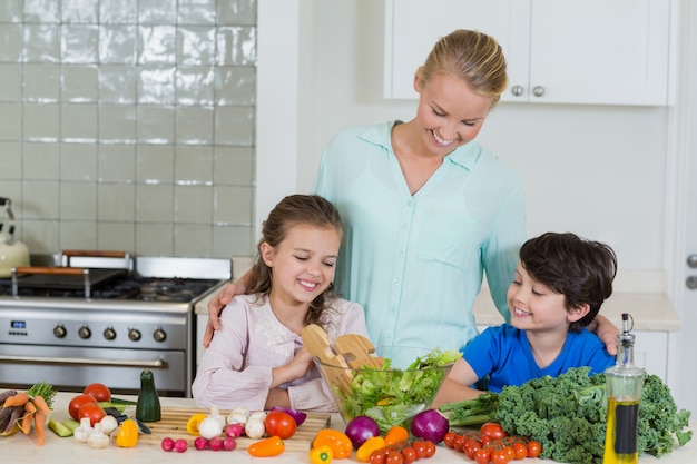 Mutter und Kinder bereiten einen Salat in der Küche vor