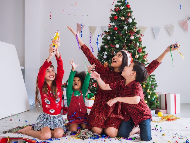 Mutter und Kinder feiern Weihnachten und haben Spaß und glücklich im Haus mit Weihnachtsbaum