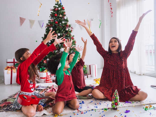 Mutter und Kinder feiern Weihnachten und haben Spaß und glücklich im Haus mit Weihnachtsbaum