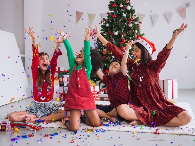 Mutter und Kinder feiern Weihnachten und haben Spaß und glücklich im Haus mit Weihnachtsbaum