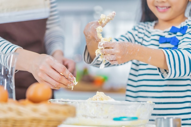 Mutter- und Kinderhand arbeiten zusammen, um Mehl und Zutat für das Kochen und Backen von Bäckereien in der heimischen Küche zu mischen.