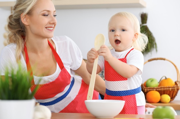 Mutter- und Kindertochter, die Teigwaren oder Salat für das Frühstück kocht. Konzept der glücklichen Familie in der Küche.