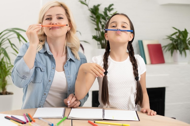 Mutter und kleine 8er-Tochter zu Hause haben Spaß beim gemeinsamen Malen mit Farben. Glückliche Mutter oder Kindermädchen und kleine Mädchen zeichnen gerne. Hobby-Konzept