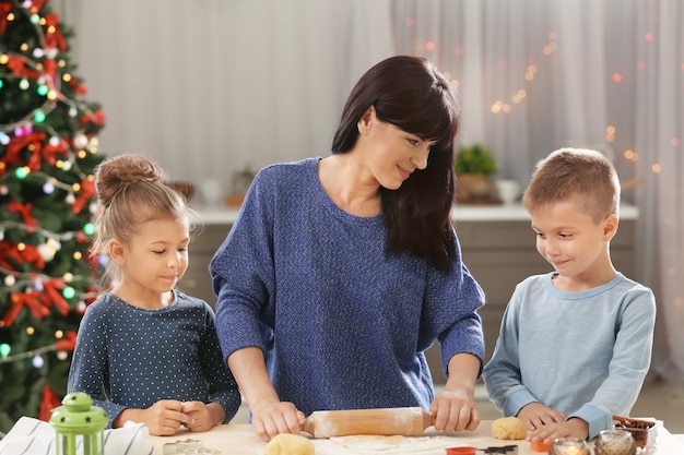 Mutter und kleine Kinder machen Weihnachtsplätzchen in der Küche