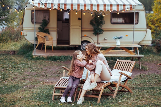 Mutter und kleine Tochter, die Spaß in der Landschaft auf Reisemobilferien küssen und haben