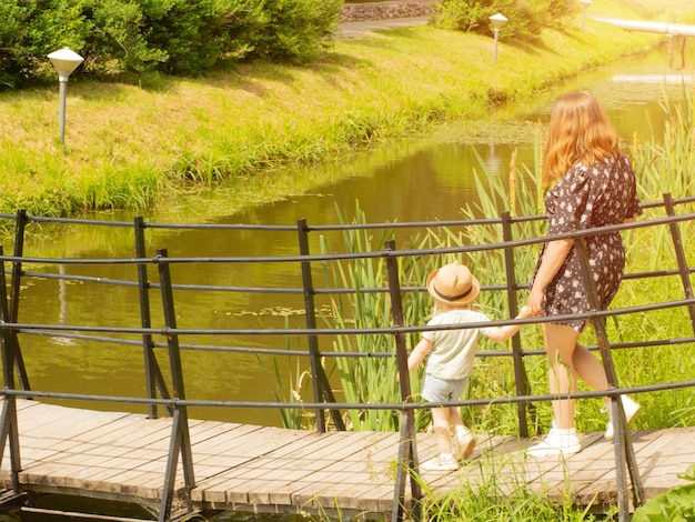 Mutter und kleine Tochter gehen an der Hand im Park spazieren