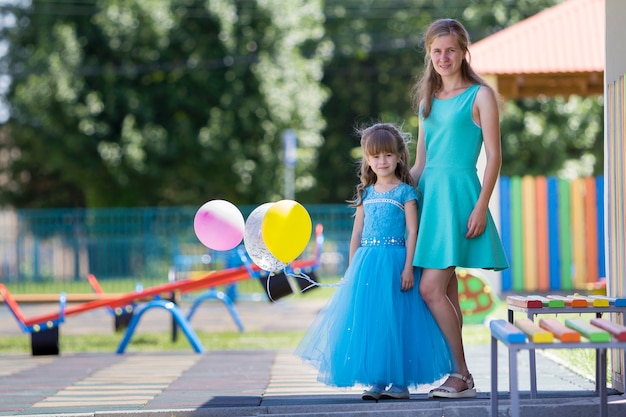 Mutter und kleine Tochter im blauen Abendkleid.