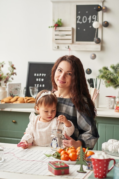 Mutter und kleine Tochter in der Küche dekoriert für das neue Jahr und Weihnachten