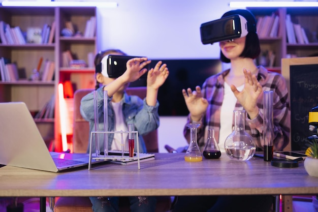 Mutter und kleine Tochter spielen mit Chemie-Labor mit VR-Brille