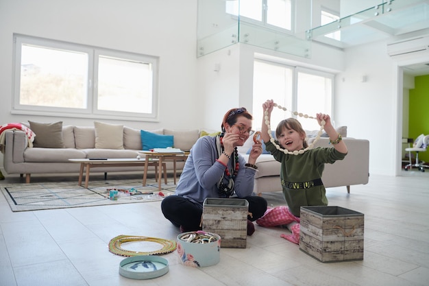 Mutter und kleine Tochter spielen mit Schmuck, während sie zu Hause in der Coronavirus-Quarantäne bleiben