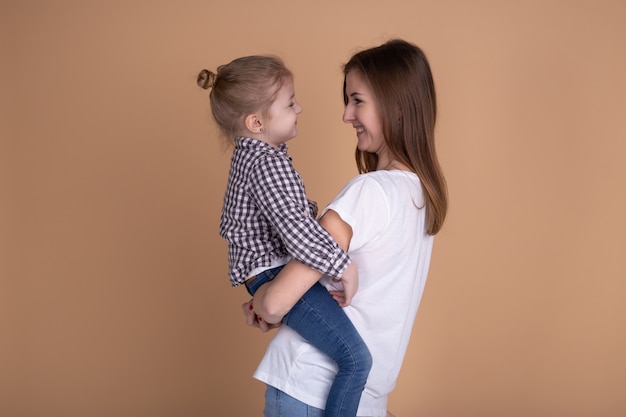 Mutter und kleine Tochter spielen zusammen auf beige neutraler Wand