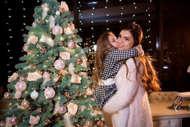 Mutter und kleine Tochter vor dem Neujahrsbaum zu Hause.