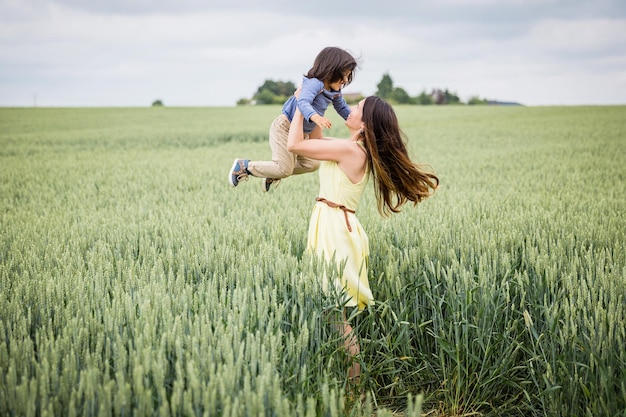 Mutter und kleiner östlicher hübscher kleiner Junge, der auf dem Feld spazieren geht