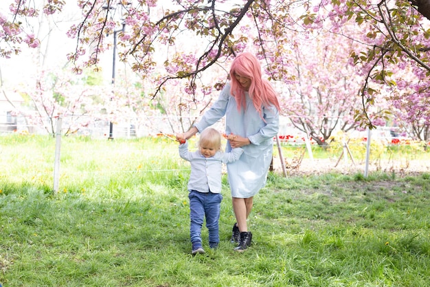 Mutter und kleiner Sohn auf Naturspaziergang im Frühlingspark Kleiner Junge und Mutter haben eine gute Zeit bei Wochenendaktivitäten in den blühenden Sakura-Gärten