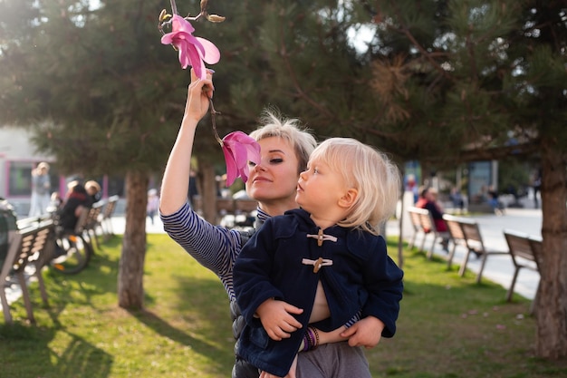 Mutter und kleiner Sohn in der Natur spielen im Frühlingspark Kleiner Junge und Mutter haben eine gute Zeit bei Wochenendaktivitäten in den blühenden Tulpenbaumgärten