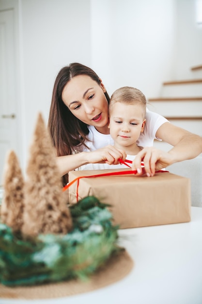 Mutter und kleiner Sohn packen ein großes Weihnachtsgeschenk