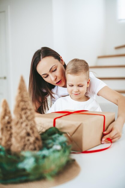 Mutter und kleiner Sohn packen ein Weihnachtsgeschenk