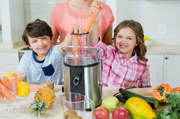 Mutter und seine zwei Kinder machen frischen Fruchtsaft in der Küche