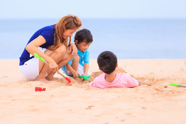 Mutter und Söhne spielen am tropischen Strand