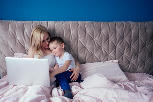 Mutter und Sohn amüsieren sich beim Sitzen mit Laptop auf dem Bett