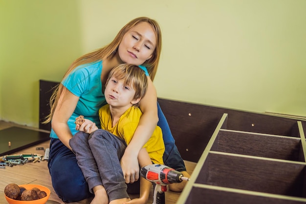 Mutter und Sohn bauen Möbel zusammen Sie machen eine Pause und essen Cupcakes Junge hilft seiner Mutter zu Hause Happy Family Konzept