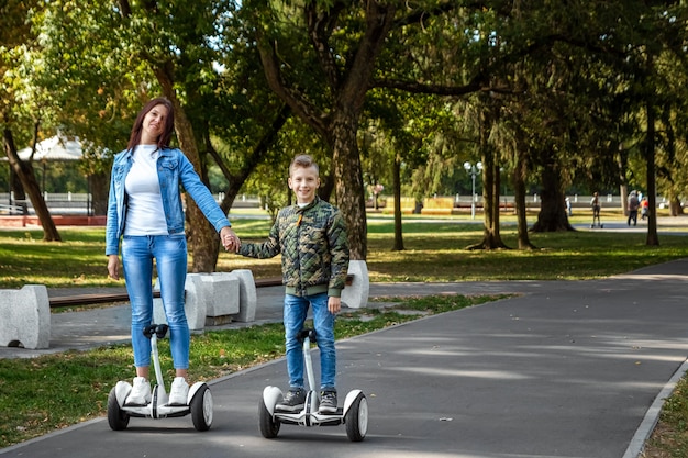 Mutter und Sohn fahren ein Hoverboard im Park