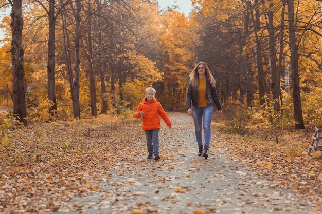 Mutter und Sohn gehen im Herbstpark spazieren und genießen die schöne Herbstnatursaison einzeln